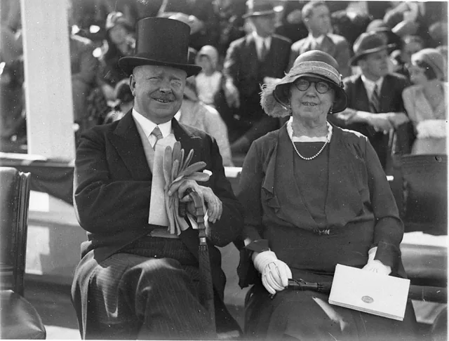Two people seated on an official dais in 1932, each face outlined by the recognition layer.