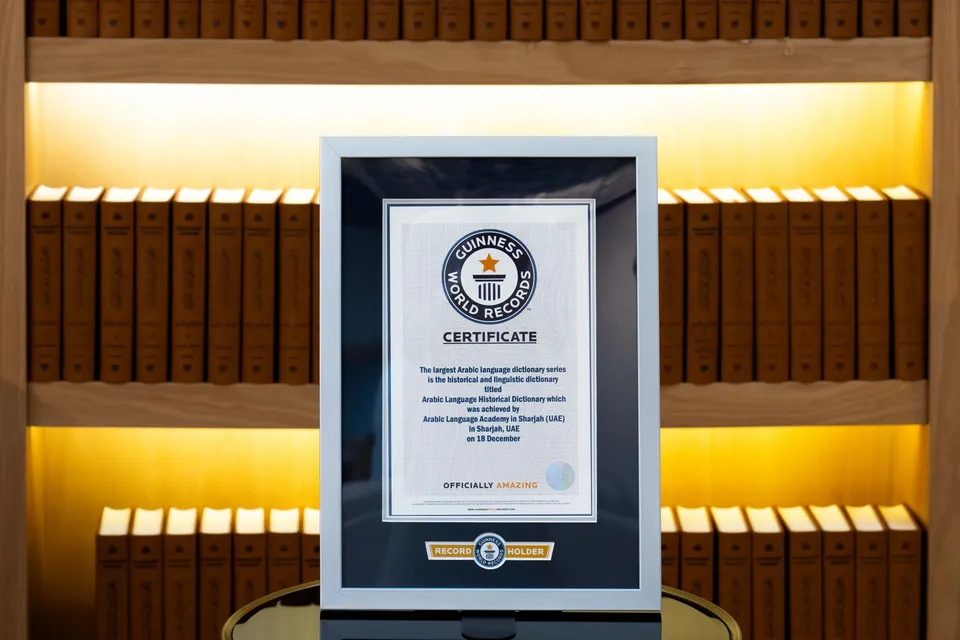 The Guinness World Records certificate in a frame, standing in front of shelves of the dictionary's volumes.