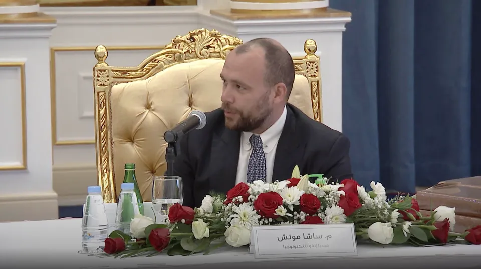 MediaINFO's chief executive speaking into a microphone at the launch table, his name plate in Arabic in front of him.